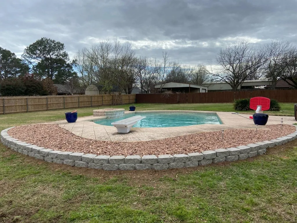 Stone-bordered decorative rock bed surrounding a backyard pool