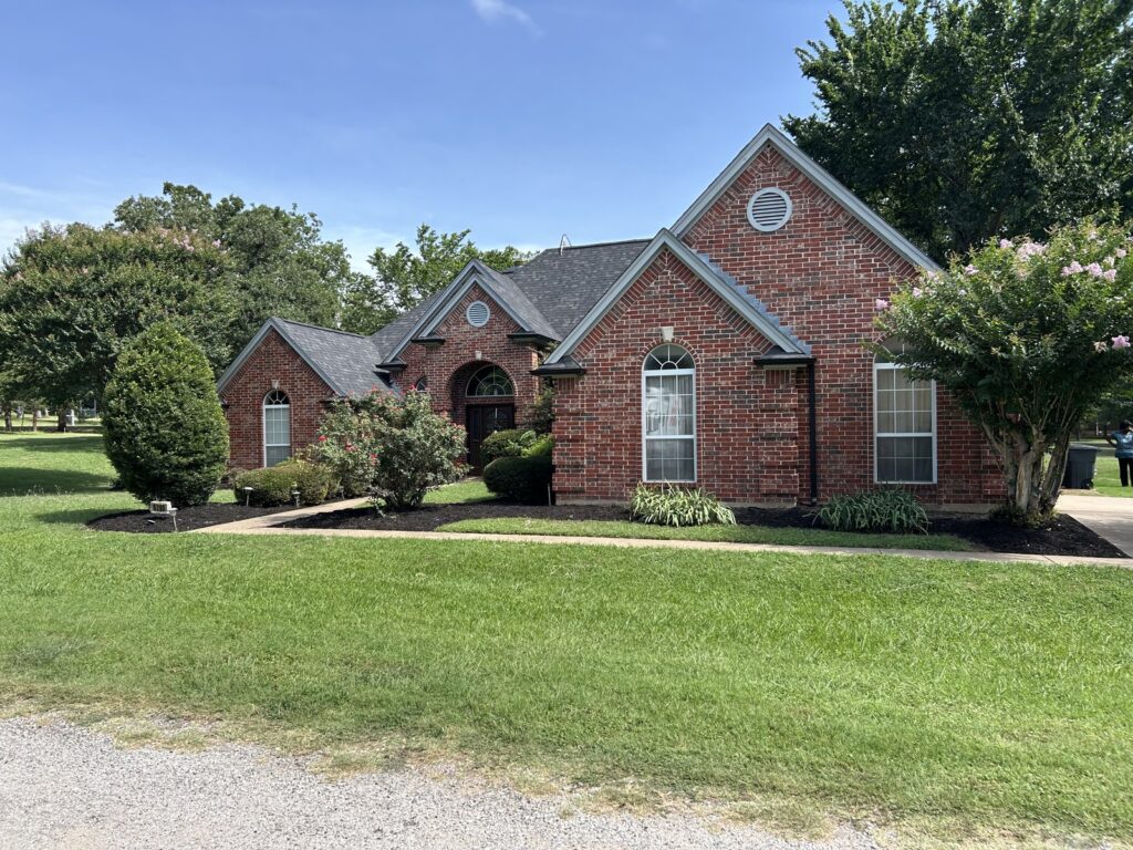 Finished residential landscape with green lawn, mature trees, shaped shrubs, and landscaped beds