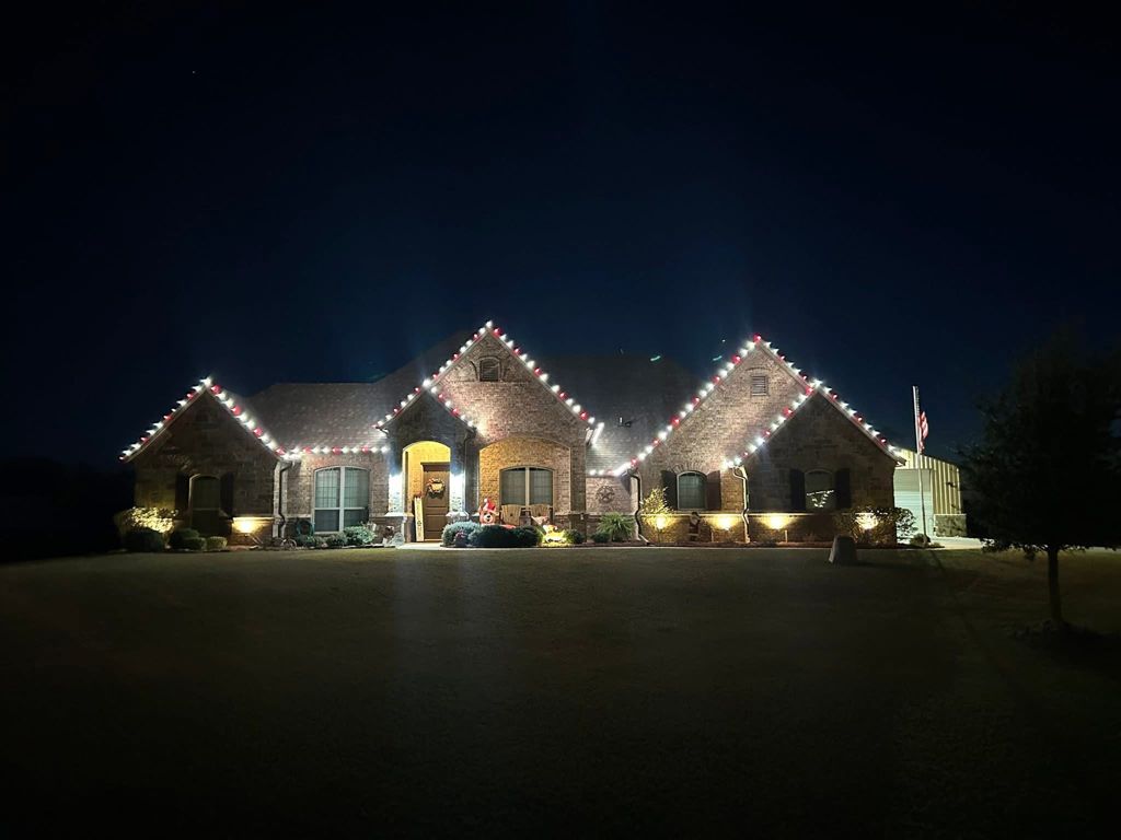 Two-story Burleson home with warm white holiday lights on every roofline