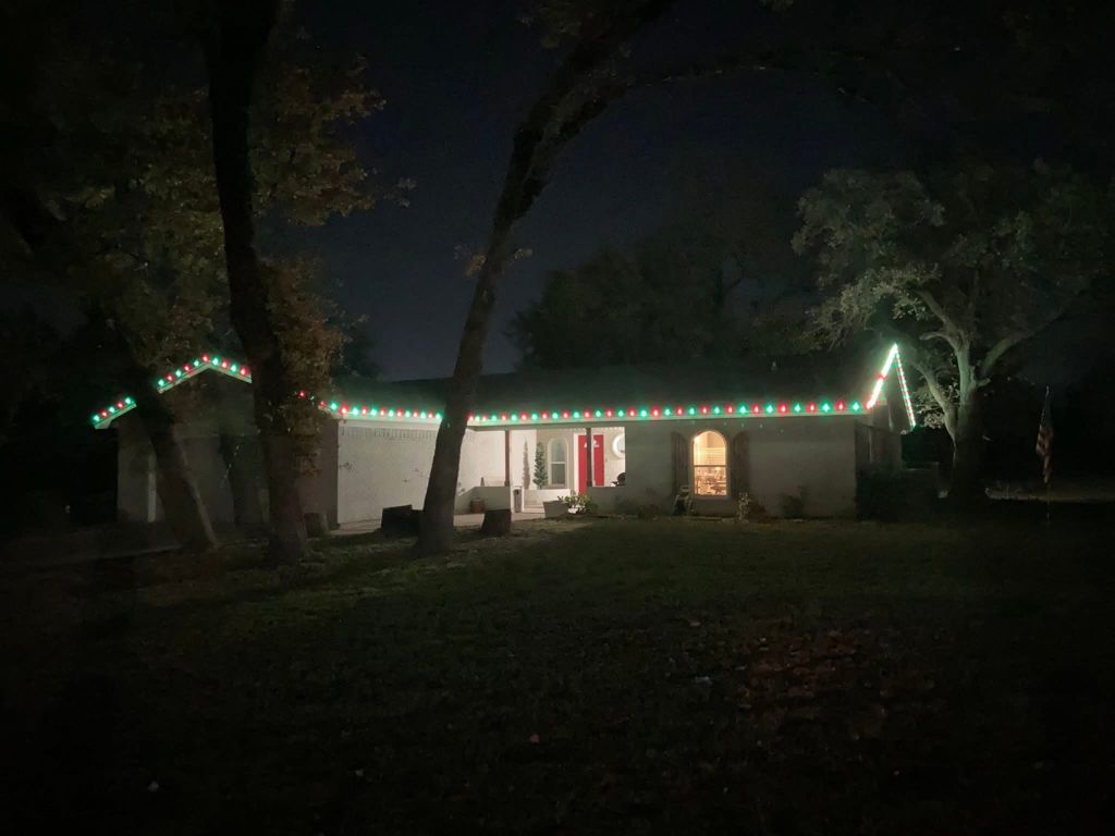 Ranch home with green and white holiday lights along the roofline