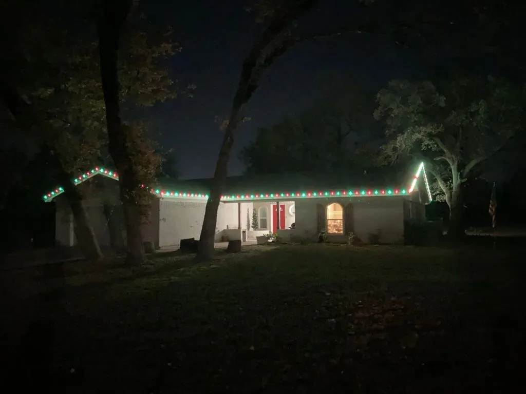Ranch home with alternating green and white Christmas lights along the roofline