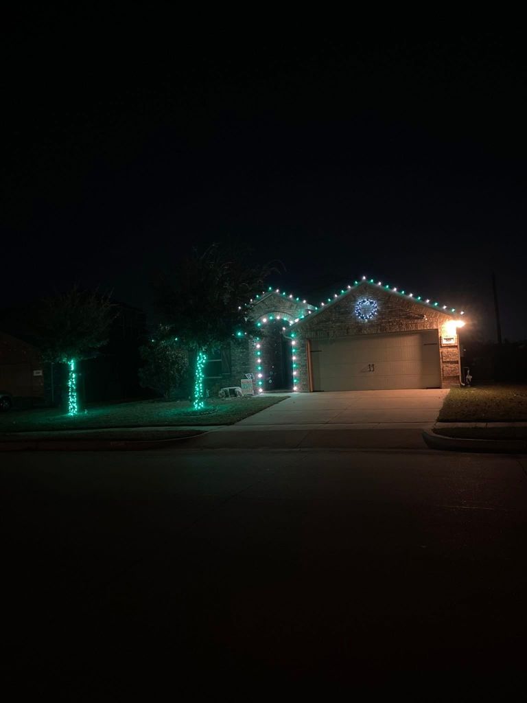 Home with teal holiday lights on the garage roofline and wrapped porch columns